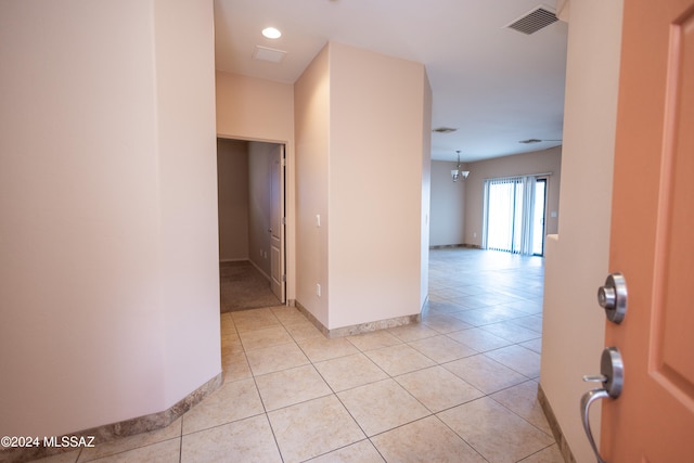 hall featuring light tile patterned floors and a notable chandelier