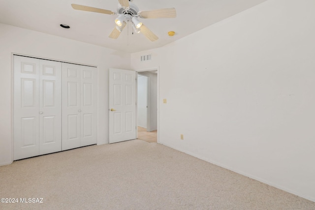 unfurnished bedroom featuring light colored carpet, a closet, and ceiling fan