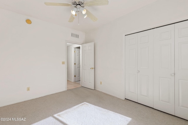 unfurnished bedroom with light carpet, a closet, and ceiling fan