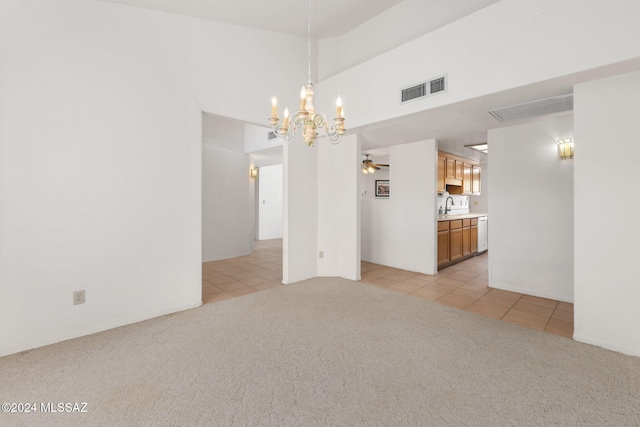 empty room featuring ceiling fan with notable chandelier, sink, and light carpet