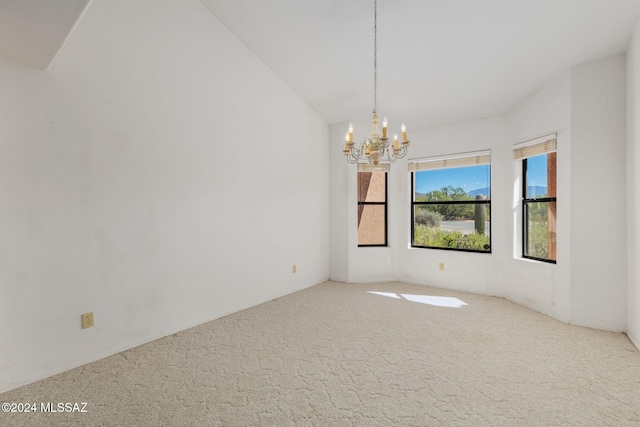 empty room with carpet, vaulted ceiling, and a chandelier