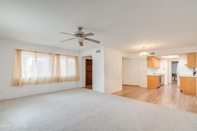 unfurnished living room featuring ceiling fan, sink, and light wood-type flooring