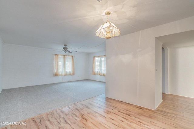 spare room featuring ceiling fan with notable chandelier and light hardwood / wood-style flooring