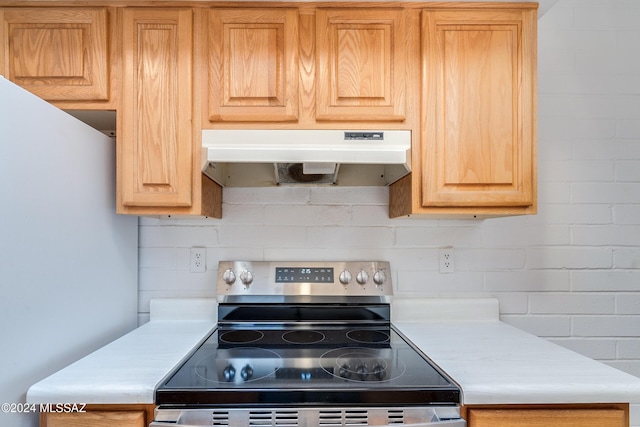 kitchen with electric stove, decorative backsplash, and light brown cabinets