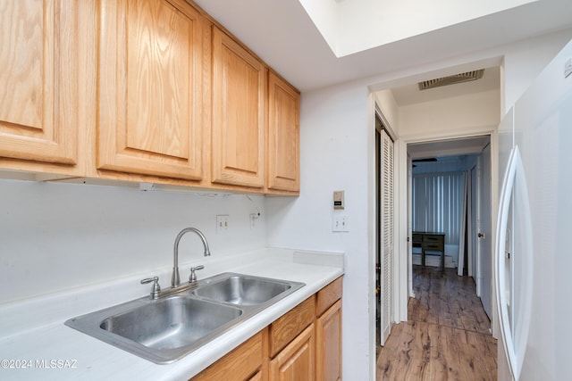 kitchen featuring light hardwood / wood-style floors, light brown cabinetry, sink, and white fridge