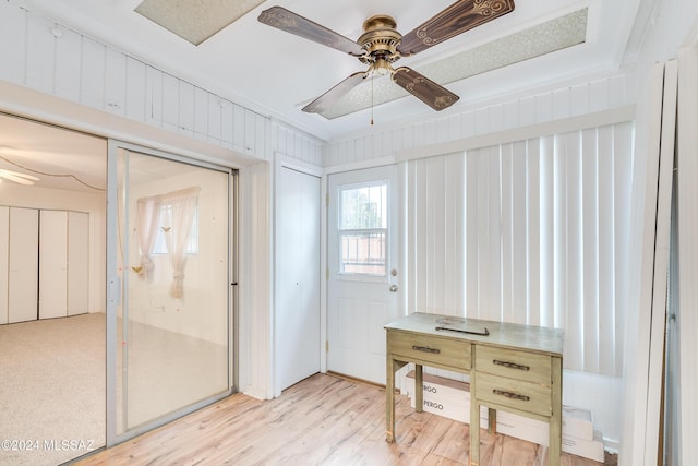 interior space with ornamental molding, wooden walls, ceiling fan, and light hardwood / wood-style flooring