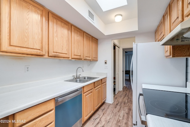 kitchen with appliances with stainless steel finishes, a skylight, sink, light hardwood / wood-style floors, and a tray ceiling