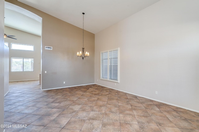 empty room with ceiling fan with notable chandelier and high vaulted ceiling