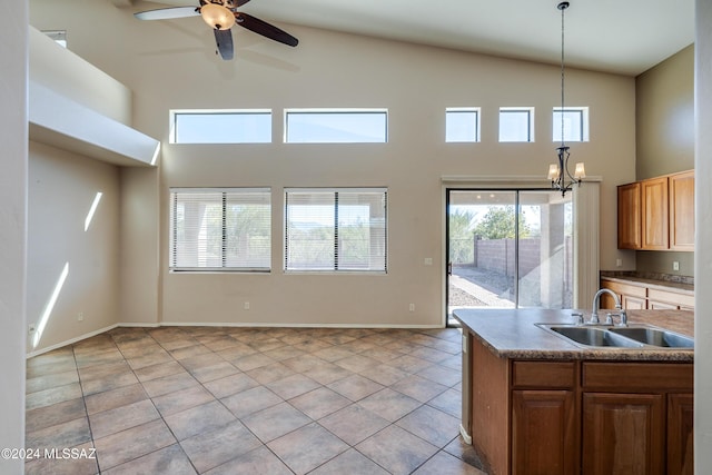 kitchen featuring decorative light fixtures, a towering ceiling, sink, and ceiling fan with notable chandelier