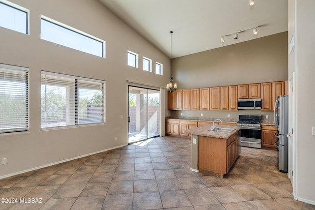 kitchen featuring pendant lighting, an inviting chandelier, a center island with sink, sink, and stainless steel appliances