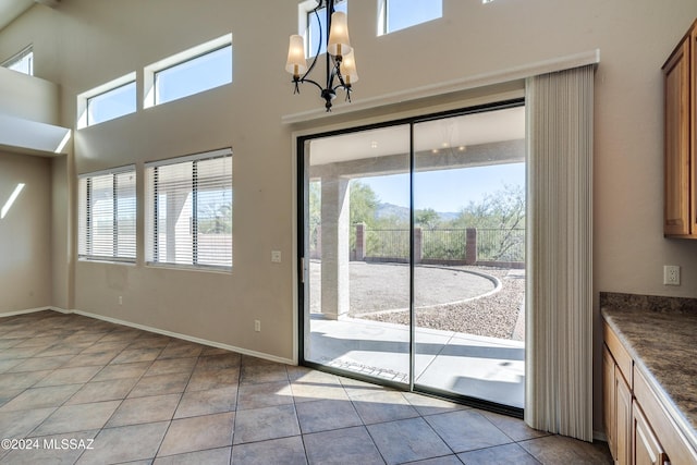 doorway to outside with an inviting chandelier and light tile patterned flooring