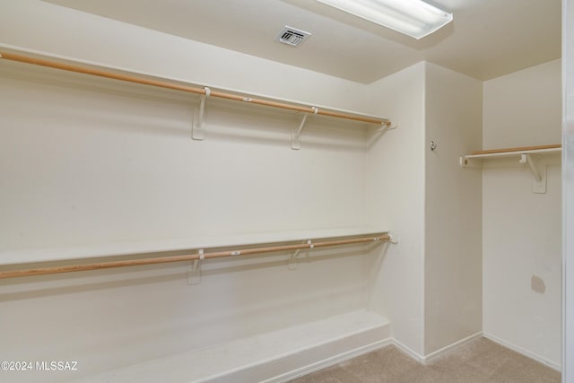 walk in closet featuring light colored carpet