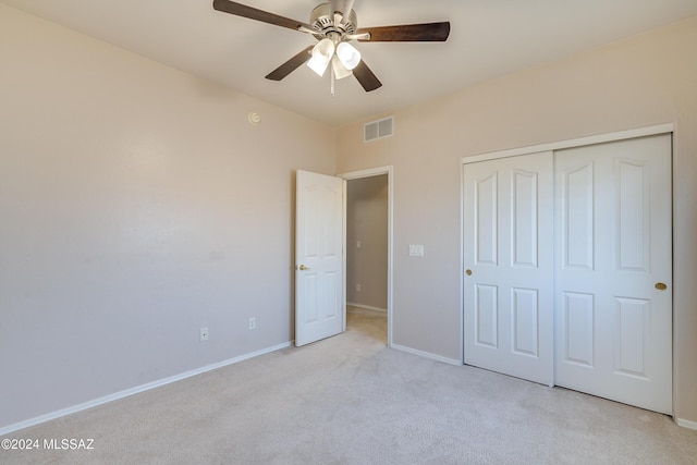 unfurnished bedroom with a closet, light colored carpet, and ceiling fan