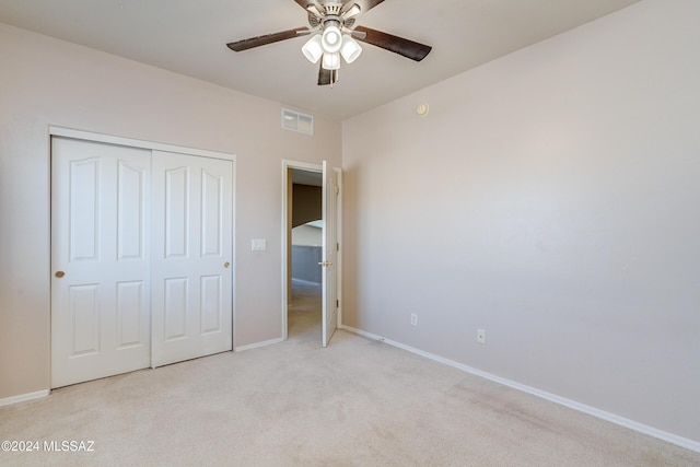 unfurnished bedroom with ceiling fan, light carpet, and a closet