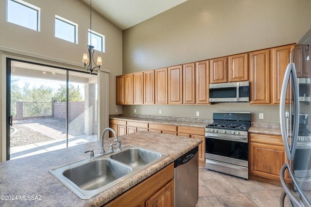 kitchen with sink, hanging light fixtures, a high ceiling, an inviting chandelier, and appliances with stainless steel finishes