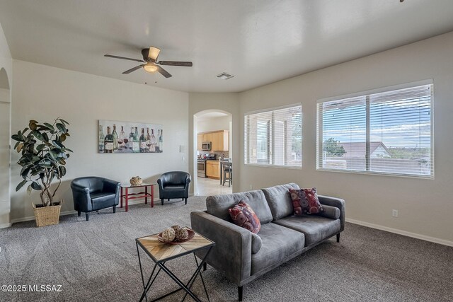 carpeted living room with decorative columns and ceiling fan