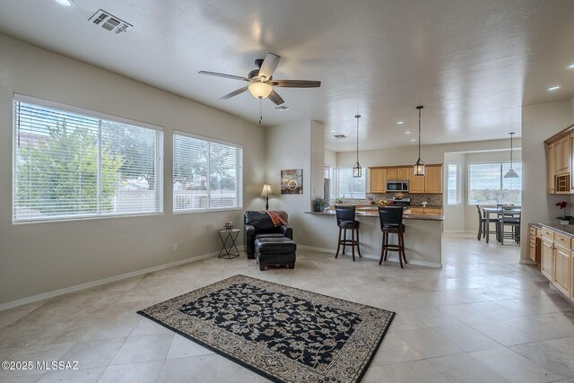 sitting room featuring ceiling fan, a tile fireplace, and light tile patterned floors