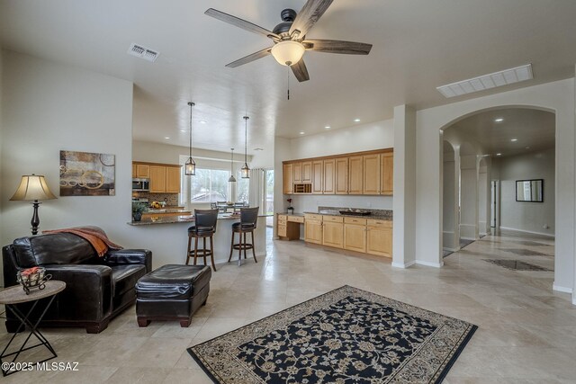 living room with a tile fireplace and ceiling fan