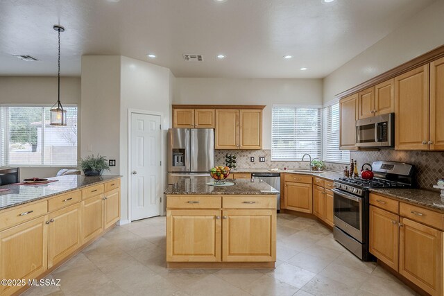 kitchen featuring a kitchen island, appliances with stainless steel finishes, pendant lighting, tasteful backsplash, and dark stone countertops