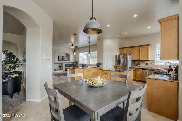 kitchen featuring appliances with stainless steel finishes, a center island, dark stone countertops, and decorative light fixtures