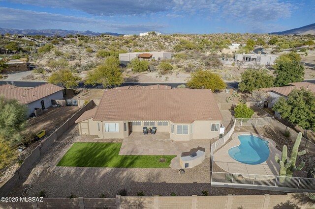 back of property with a yard, a mountain view, and a patio