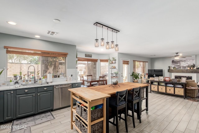 kitchen featuring gray cabinets, ceiling fan, decorative light fixtures, stainless steel dishwasher, and sink