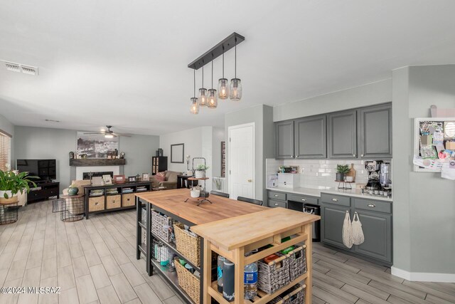 kitchen with decorative light fixtures, backsplash, ceiling fan with notable chandelier, and gray cabinets