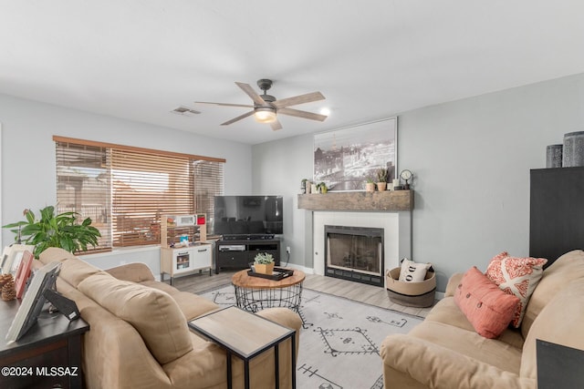 living room featuring ceiling fan and a tile fireplace