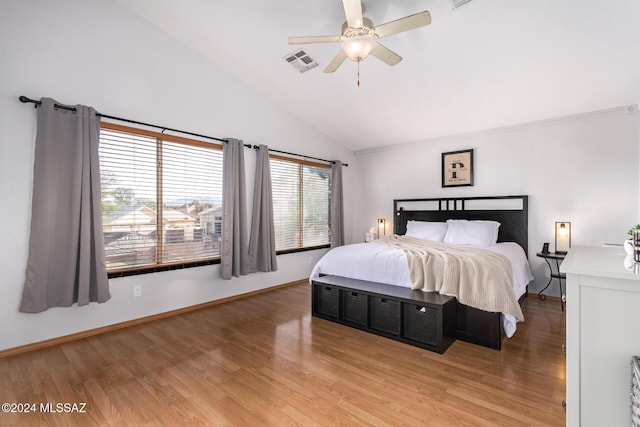 bedroom with ceiling fan, vaulted ceiling, multiple windows, and hardwood / wood-style floors