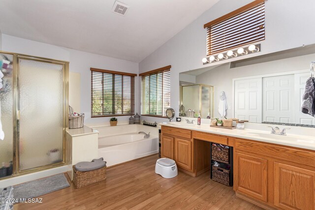 bathroom featuring vanity, vaulted ceiling, independent shower and bath, and hardwood / wood-style flooring