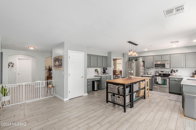 kitchen featuring decorative light fixtures, gray cabinets, stainless steel appliances, and tasteful backsplash