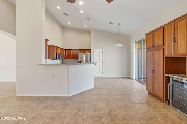 kitchen with light tile patterned flooring, light stone counters, decorative light fixtures, high vaulted ceiling, and appliances with stainless steel finishes