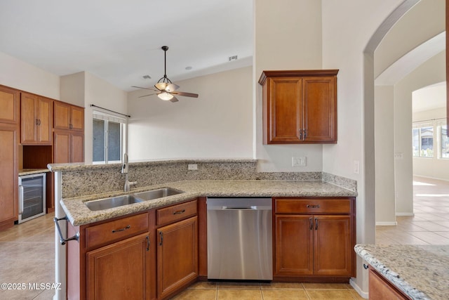 kitchen featuring sink, wine cooler, stainless steel dishwasher, light tile patterned floors, and light stone counters