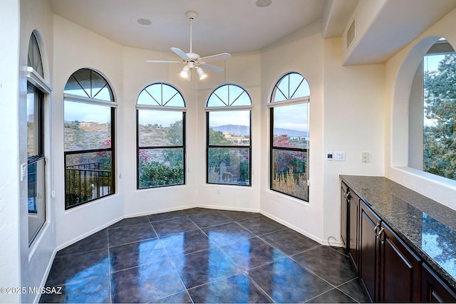 unfurnished sunroom featuring ceiling fan and a healthy amount of sunlight