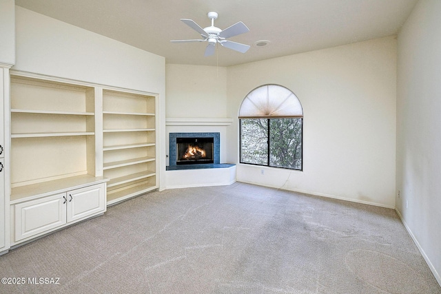 unfurnished living room with light carpet, built in features, and ceiling fan