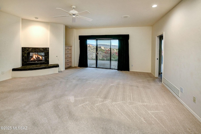 unfurnished living room with light colored carpet and ceiling fan