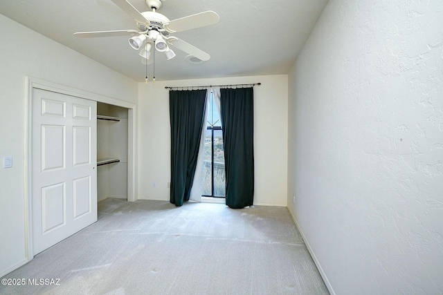 unfurnished bedroom with light carpet, a closet, and ceiling fan