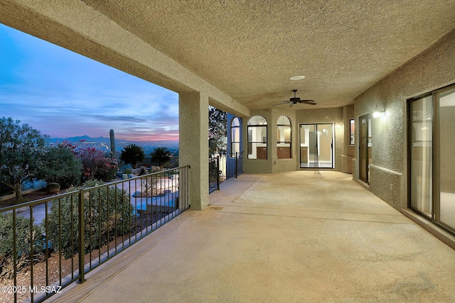 patio terrace at dusk with ceiling fan and a balcony