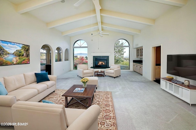 living room featuring a tile fireplace, light carpet, high vaulted ceiling, and ceiling fan