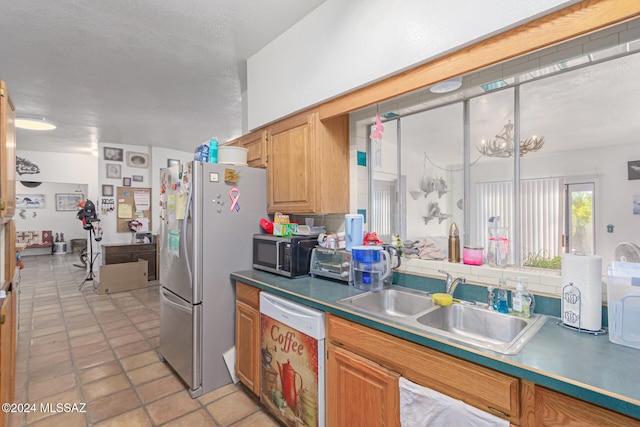 kitchen featuring sink, light tile patterned floors, a textured ceiling, stainless steel appliances, and a chandelier