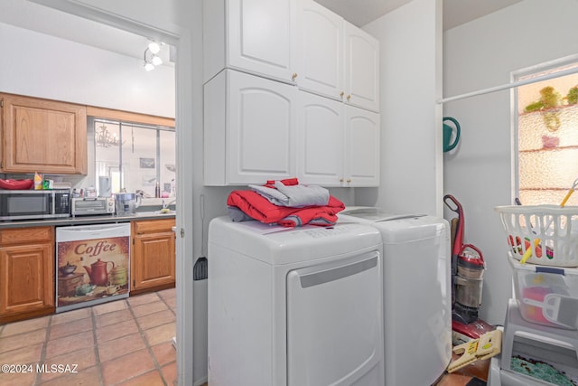 clothes washing area featuring cabinets, light tile patterned floors, and washing machine and clothes dryer