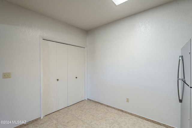 unfurnished bedroom with stainless steel fridge and a closet