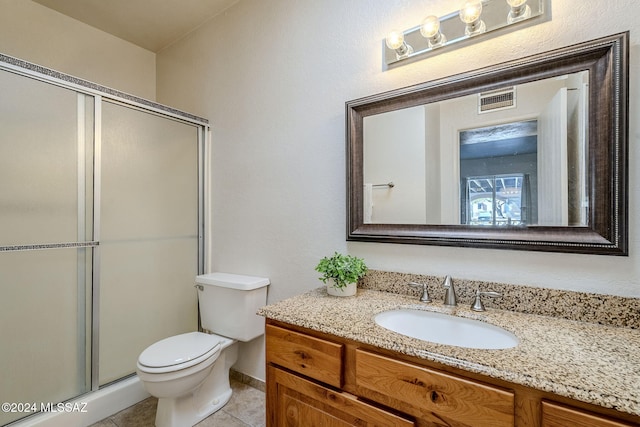 bathroom with tile patterned floors, a shower with door, vanity, and toilet