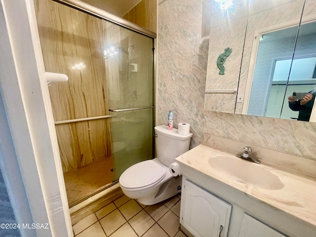 bathroom featuring vanity, tile patterned flooring, toilet, tasteful backsplash, and a shower with shower door