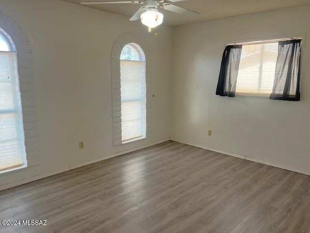 empty room featuring hardwood / wood-style floors, ceiling fan, and a healthy amount of sunlight