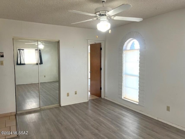 unfurnished bedroom with hardwood / wood-style floors, a textured ceiling, a closet, and ceiling fan