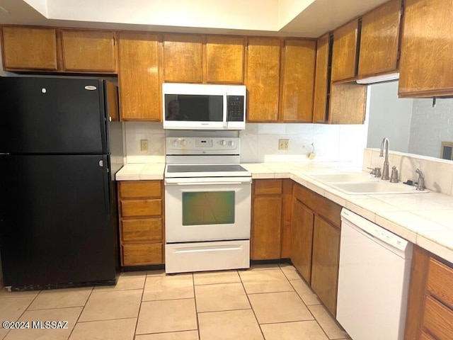 kitchen featuring tile countertops, white appliances, sink, decorative backsplash, and light tile patterned flooring