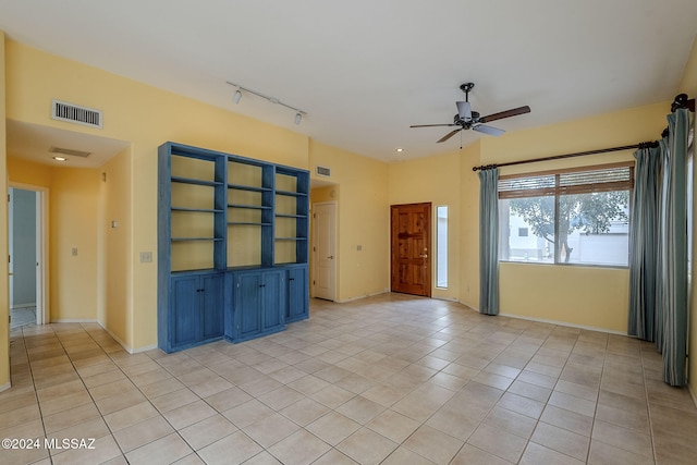 tiled empty room featuring rail lighting and ceiling fan