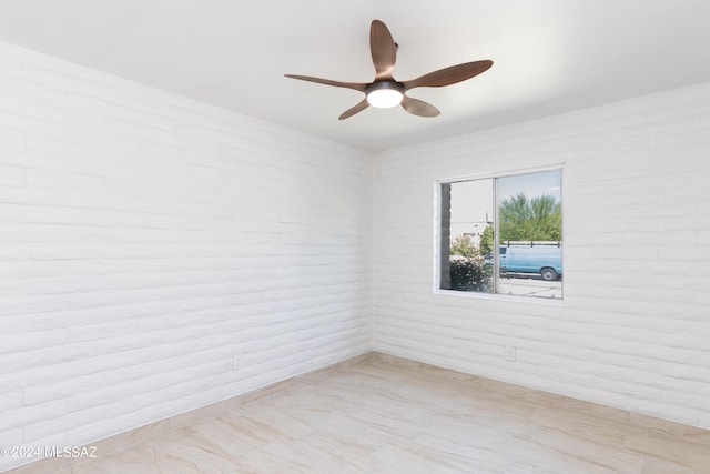 unfurnished room featuring ceiling fan and brick wall