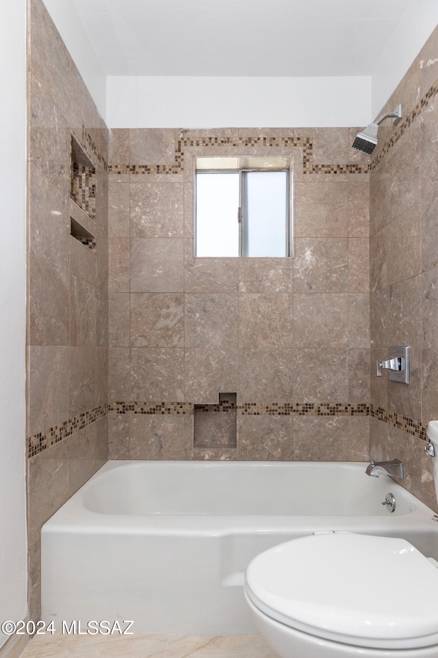 bathroom featuring tile patterned floors, tiled shower / bath combo, and toilet